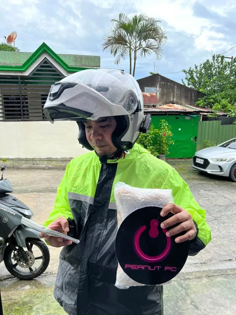 Delivery rider holding a Peanut PC parcel and shop bag