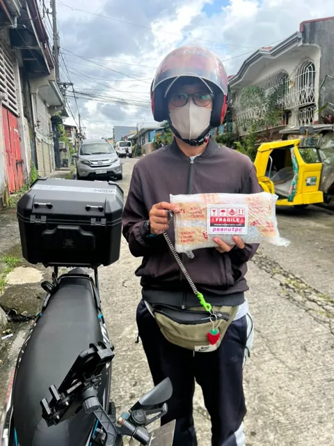 Delivery rider in a pink helmet holding a wrapped parcel